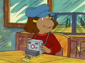 Francine wearing a blue beret and holding a camera.